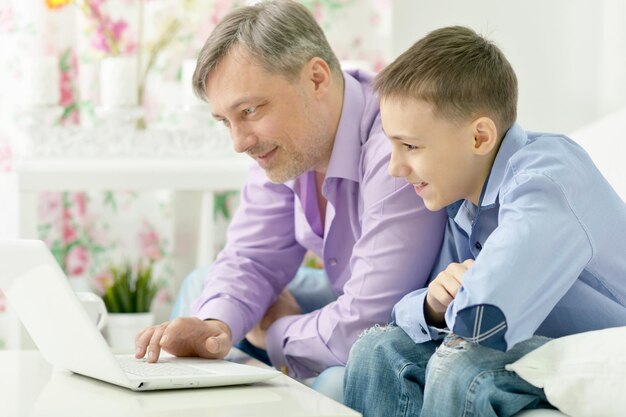 retrato, de, un, sonriente, padre e hijo, usar la computadora portátil