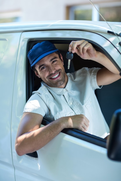 Foto retrato de sonriente repartidor mostrando las llaves del auto