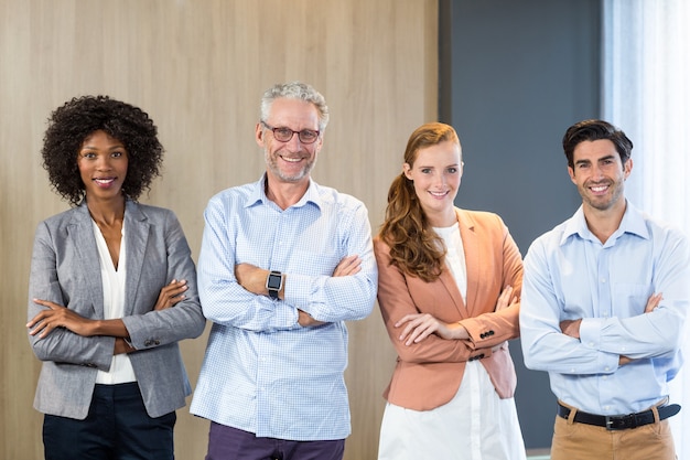 Retrato de sonrientes empresarios de pie junto con los brazos cruzados