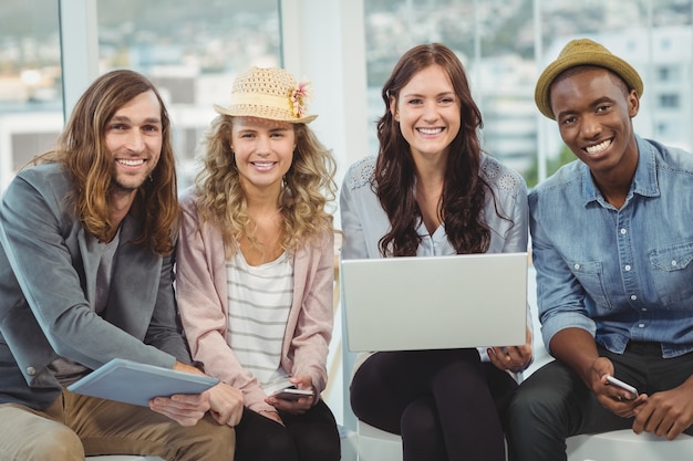 Retrato de sonrientes empresarios con portátil y tableta digital mientras está sentado en la silla