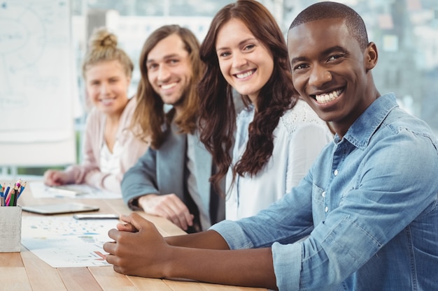 Retrato de sonrientes empresarios sentado en fila en el escritorio