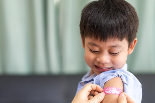 Retrato de sonrisa feliz vacunados niños pequeños asiáticos niños de 5 a 11 años posando mostrar brazo con yeso médico después de la vacuna inyectable Protección Covid19 vacunación contra el coronavirus niño