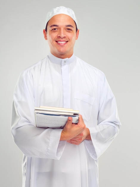 Retrato de sonrisa de hombre islámico y libros para aprender de fondo blanco para la cultura árabe Sonrisa de joven y esperanza de fe de religión o estudiar para la educación musulmana aislada en estudio