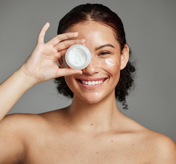 Foto retrato de sonrisa de mujer negra y crema para la belleza, el bienestar, los ojos, la dermatología cosmética y el producto de spa en un estudio gris. crema hidratante facial para niña africana feliz y protector solar spf o brillo de piel de lujo.