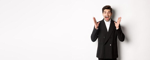 Foto retrato de un sorprendido y guapo hombre de negocios en traje reaccionando a la promoción de las vacaciones mirando asombrado a la persona