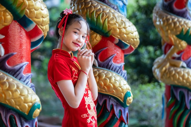 Retrato sorri Menina asiática bonitinha vestindo decoração tradicional de vestido vermelho cheongsam para o festival do ano novo chinês celebra a cultura da china no santuário chinês