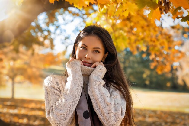 Retrato sorridente de uma jovem de pé no parque durante o outono