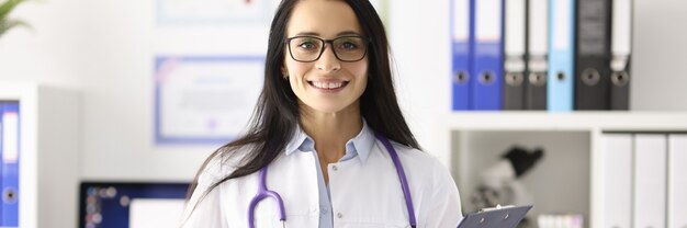 Retrato sorridente médica de jaleco branco em consultório médico. conceito de centros médicos