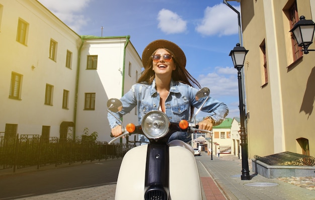 Foto retrato sorrindo linda garota sentada na scooter retrô.