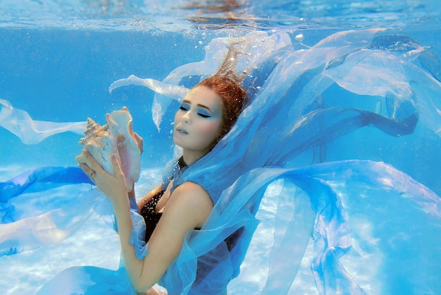 Retrato submarino de moda de una hermosa joven vestida de azul