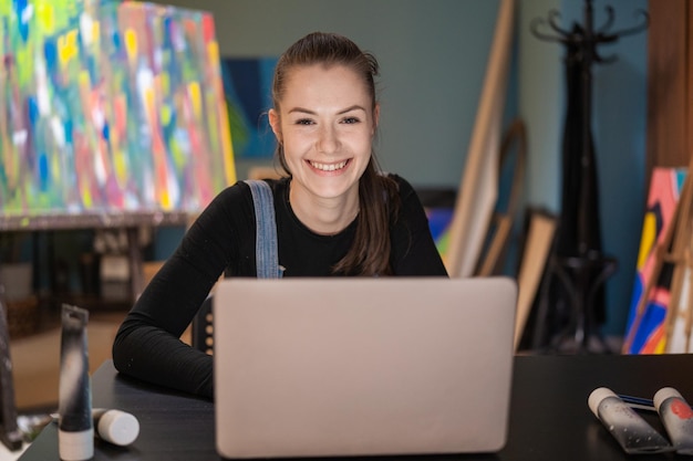 Retrato de una talentosa estudiante de arte sonriente que toma clases remotas haciendo un proyecto desde la pintura de su casa