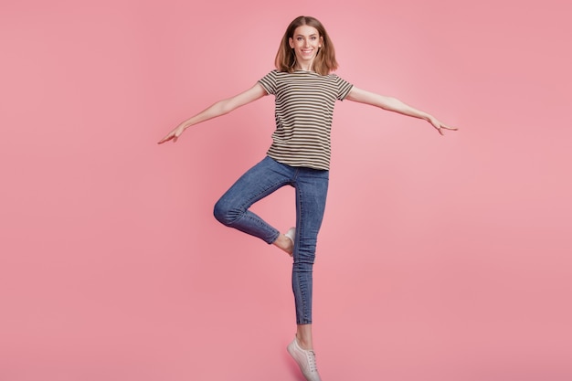 Retrato de tamaño completo de mujer joven alegre feliz sonrisa positiva equilibrio saltar aislado sobre fondo de color rosa