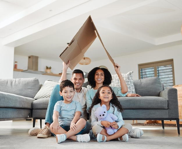 Retrato de techo de cartón y una familia en un salón para seguridad y refugio como familia Casa feliz y madre padre e hijos con refugio en una sala de estar para un seguro juntos