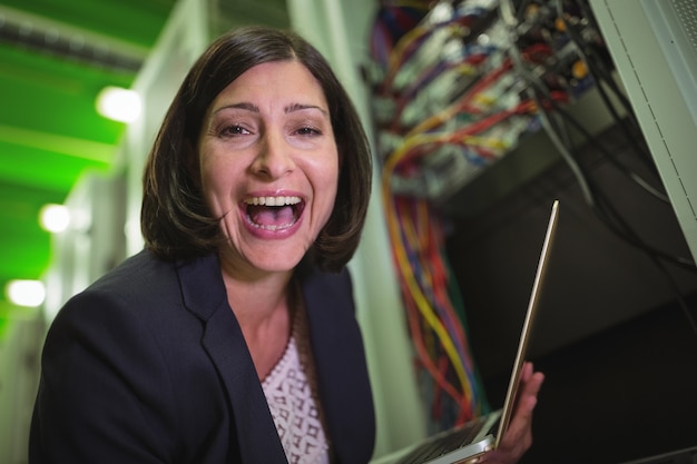 Retrato del técnico feliz que sostiene el ordenador portátil