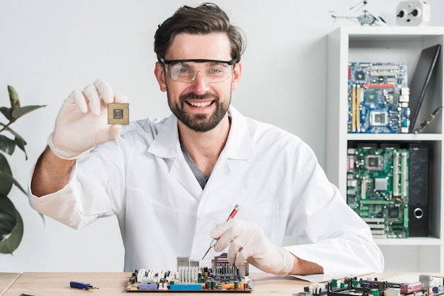 Retrato de un técnico de sexo masculino joven feliz que sostiene el chip de ordenador