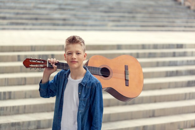 Foto retrato teenager boy con guitarra acústica en el parque.