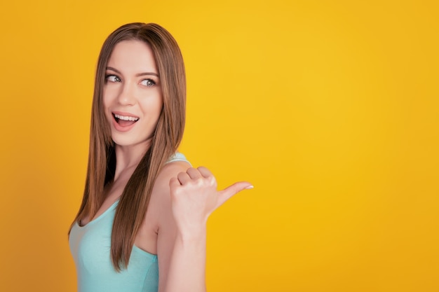 Retrato de tierna dama encantadora curiosa directa pulgar espacio en blanco asesorar solución sobre fondo amarillo