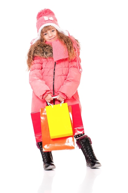 Retrato a toda longitud de una niña con ropa de invierno con bolsas de compras aisladas sobre un fondo blanco