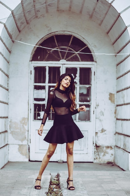 Retrato en toda su longitud de una mujer joven con vestido negro en la ciudad