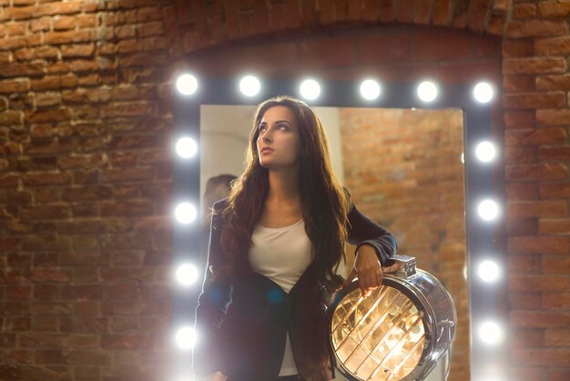 Foto retrato en toda su longitud de una mujer de pie contra un edificio iluminado