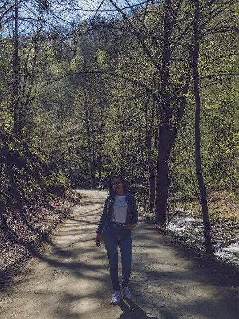 Foto retrato en toda su longitud de una mujer en un sendero en el bosque