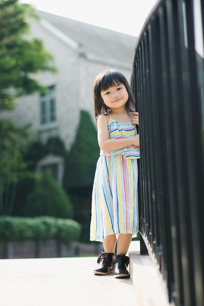 Retrato en toda su longitud de una niña de pie junto a las barandillas