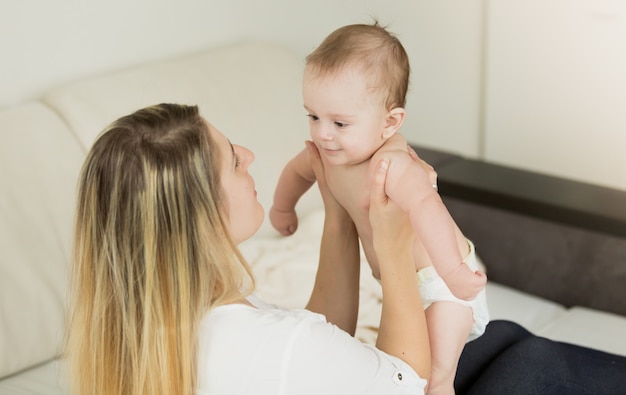 Retrato de tonos de feliz madre sosteniendo al bebé en las manos