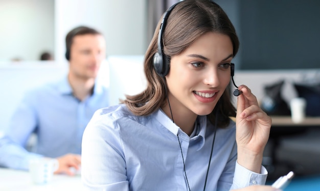 Retrato de trabajador de call center acompañado de su equipo. Operador de soporte al cliente sonriente en el trabajo.