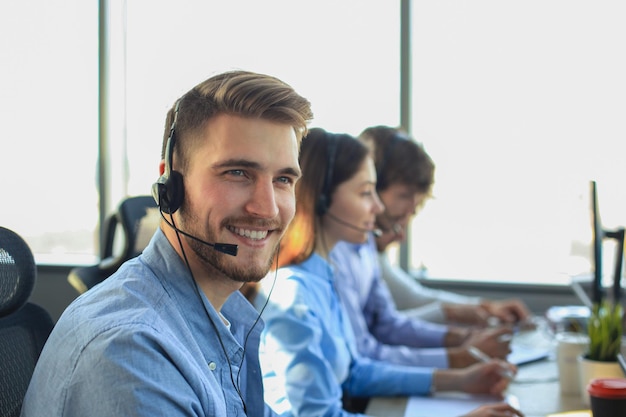 Retrato del trabajador del centro de llamadas acompañado por su equipo Operador de atención al cliente sonriente en el trabajo