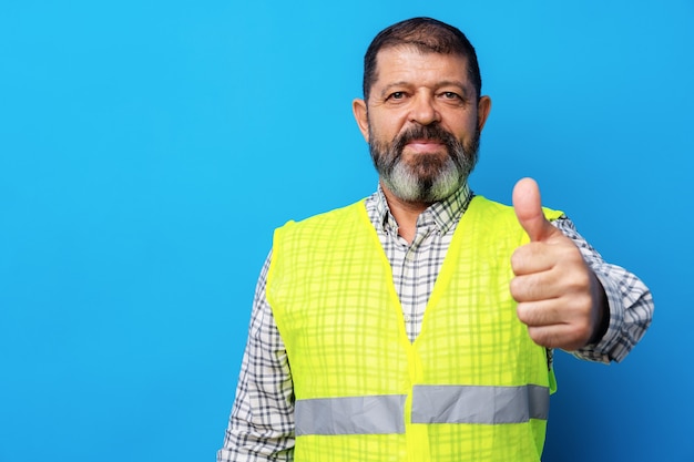 Retrato de trabajador de la construcción senior en chaleco amarillo en studio