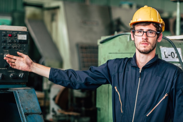 El retrato del trabajador feliz joven americano disfruta de la sonrisa feliz para trabajar en una fábrica industrial pesada. Postura actual de la mano.