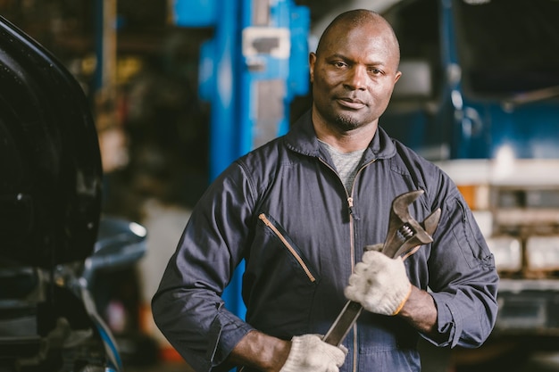 Retrato trabajador de garaje mecánico negro africano comprobar el personal del equipo de servicio automático inteligente seguro de pie