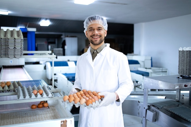 Retrato de un trabajador de la granja de huevos con caja de cartón con huevos frescos