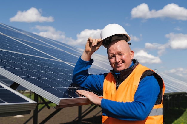 Retrato de un trabajador de una granja solar apoyado contra los paneles