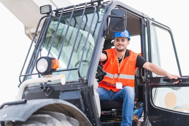 Retrato de un trabajador manual sonriente sentado en un vehículo