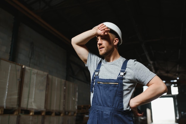 Retrato de un trabajador masculino feliz en un almacén parado entre estantes