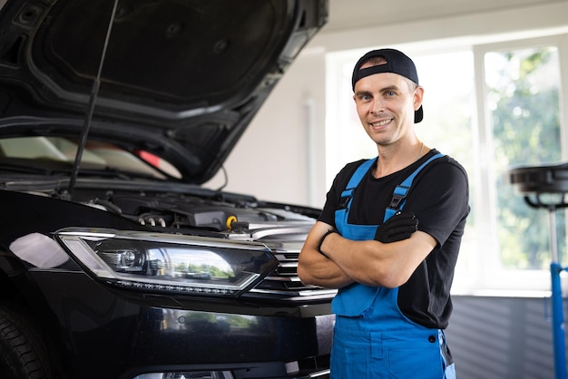 Retrato trabajador mecánico feliz en uniforme azul y gorra del centro de servicio automático