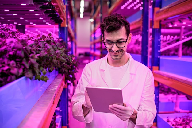 Retrato de trabajador con tableta en granja acuapónica, negocios sostenibles e iluminación artificial.