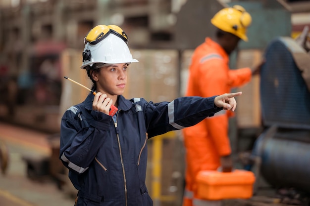 Foto retrato de un trabajador técnico ferroviario con chaleco de seguridad y casco trabajando y usando un walkie-talkie