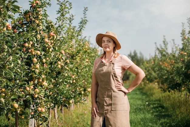 Retrato de una trabajadora agricultora sonriente recogiendo manzanas maduras frescas en el jardín de la huerta durante la cosecha de otoño Tiempo de cosecha