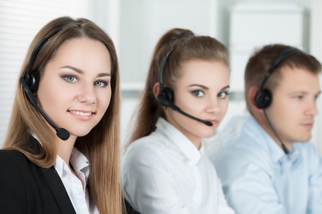 Retrato de trabajadora de call center acompañada de su equipo. Operador de soporte al cliente sonriente en el trabajo. Concepto de ayuda y soporte