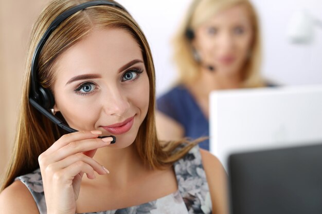 Retrato de trabajadora de call center acompañada de su equipo. Operador de soporte al cliente sonriente en el trabajo. Concepto de ayuda y soporte