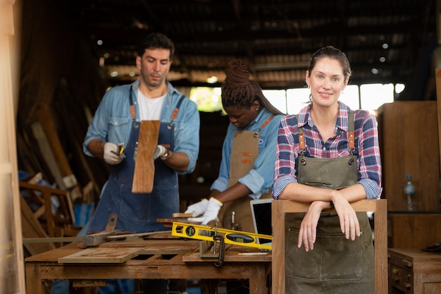 Foto retrato de una trabajadora carpintero de pie frente a su colega en el taller