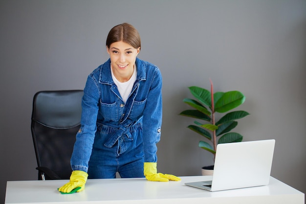 Retrato de una trabajadora feliz limpiando el escritorio de la computadora