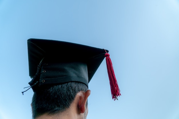 Retrato traseiro de graduado vestindo um chapéu negro.