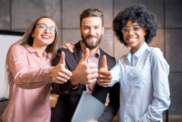 Retrato de tres compañeros de trabajo multiétnicos felices juntos en la oficina