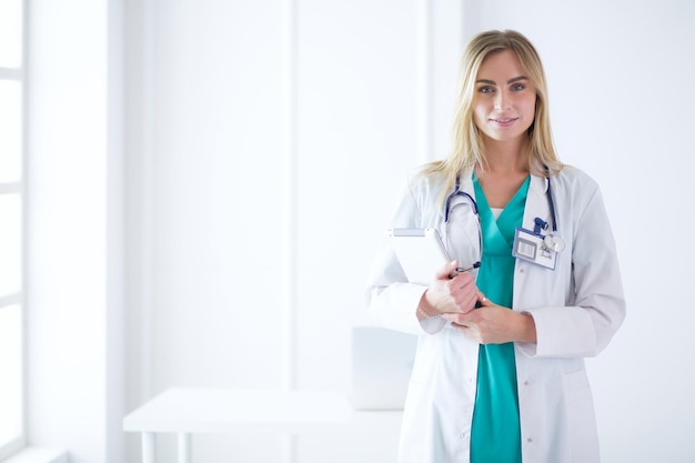 Retrato de tres doctoras confiadas de pie con los brazos cruzados en el consultorio médico