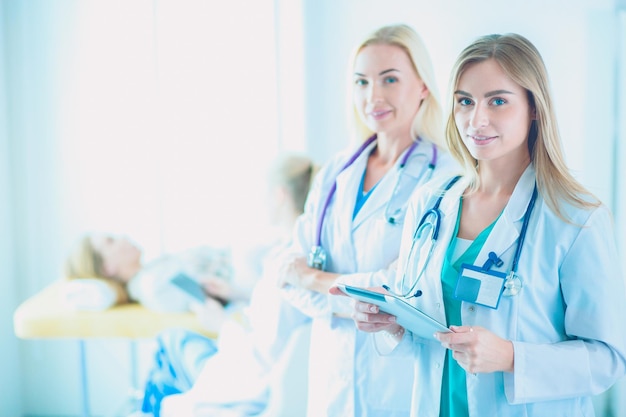 Retrato de tres doctoras confiadas de pie con los brazos cruzados en el consultorio médico