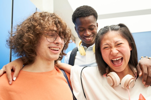 Retrato de tres estudiantes multirraciales mirando a la cámara sonriendo en una escuela secundaria