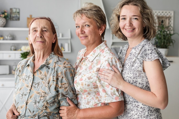 Foto retrato de tres generaciones de mujeres mirando a la cámara de pie juntos